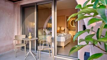 Une chambre d’hôtel moderne dotée d’une grande porte-fenêtre coulissante donnant sur un balcon avec deux chaises et une table.