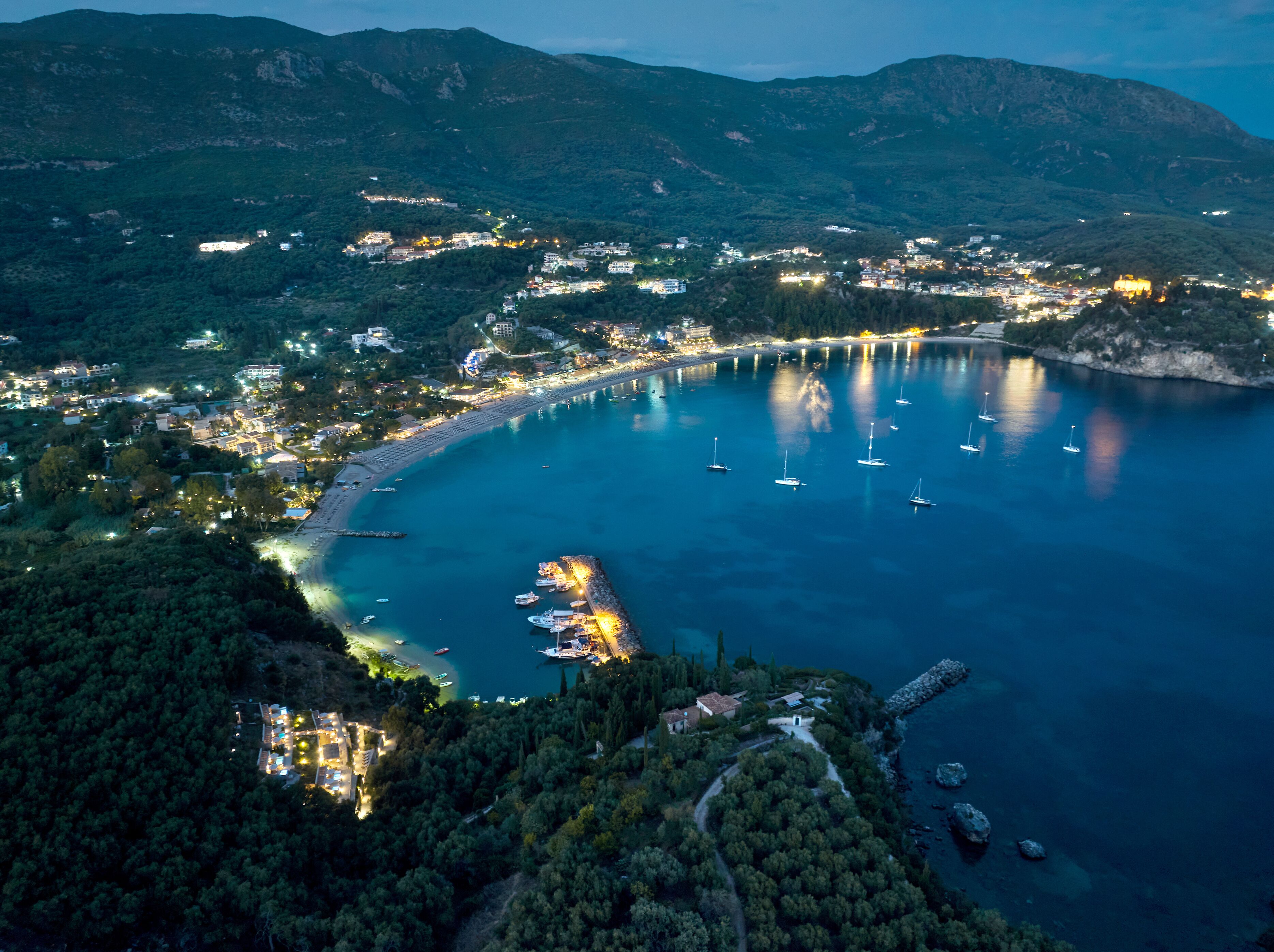 An aerial view of a coastal town with a marina, boats, and buildings.