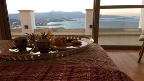 A bed with a tray of cookies and two cups on a window ledge overlooking a scenic view. - Endless View Villa close to the beach (Agios Nikolaos)