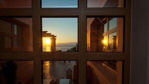 A hotel room with a view of the sunset over the water, large windows, and a balcony with a railing. - Endless View Villa close to the beach (Agios Nikolaos)