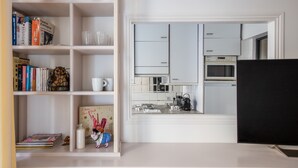 Una cucina moderna con mobili bianchi, un forno a microonde e una macchina da caffè.