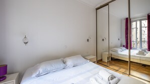 Camera d'albergo con un letto grande, un comodino, uno specchio e vista attraverso una porta in vetro.