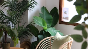 Una habitación con una mesa redonda de madera, una silla de mimbre y una planta en maceta.