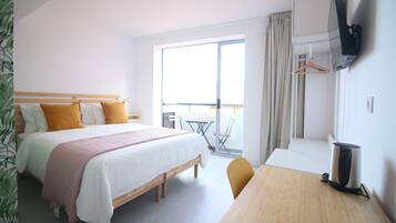 Une chambre d’hôtel comprenant un lit, un bureau, un téléviseur fixé au mur et un balcon avec une table et des chaises.