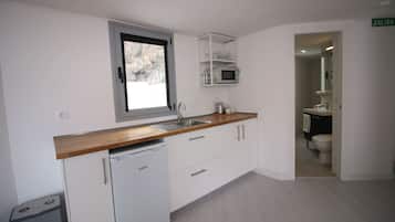 Una cocina moderna con armarios blancos, encimera de madera, microondas integrado y una ventana.
