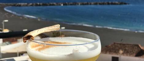 A cocktail on a balcony with a view of the ocean and a beach.