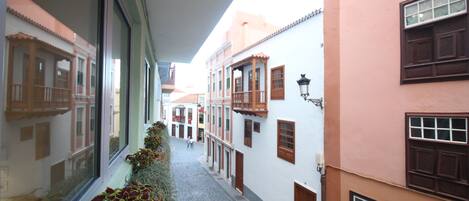 Eine enge Straße mit Häusern an beiden Seiten, ein Kopfsteinpflasterweg und ein Fenster mit Pflanzen auf der linken Seite.
