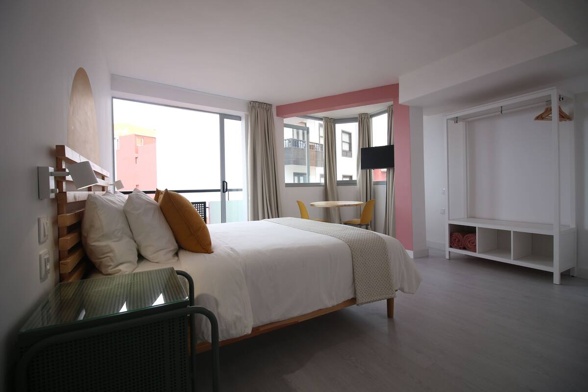 Ein modernes Hotelzimmer mit einem großen Bett, einem kleinen Tisch und einer Sitzecke.