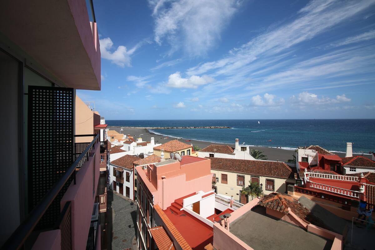 Eine Küstenstadt mit Häusern an der Straße und Blick auf das Meer.