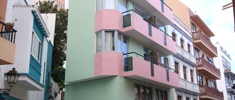 Un edificio a più piani con balconi, un caffè a livello strada e una strada acciottolata.