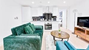 A modern living room with a green sofa, a coffee table, and a TV on a wooden stand. - Cosy 1 Bedroom Apartment in Burton-on-Trent (Burton upon Trent)