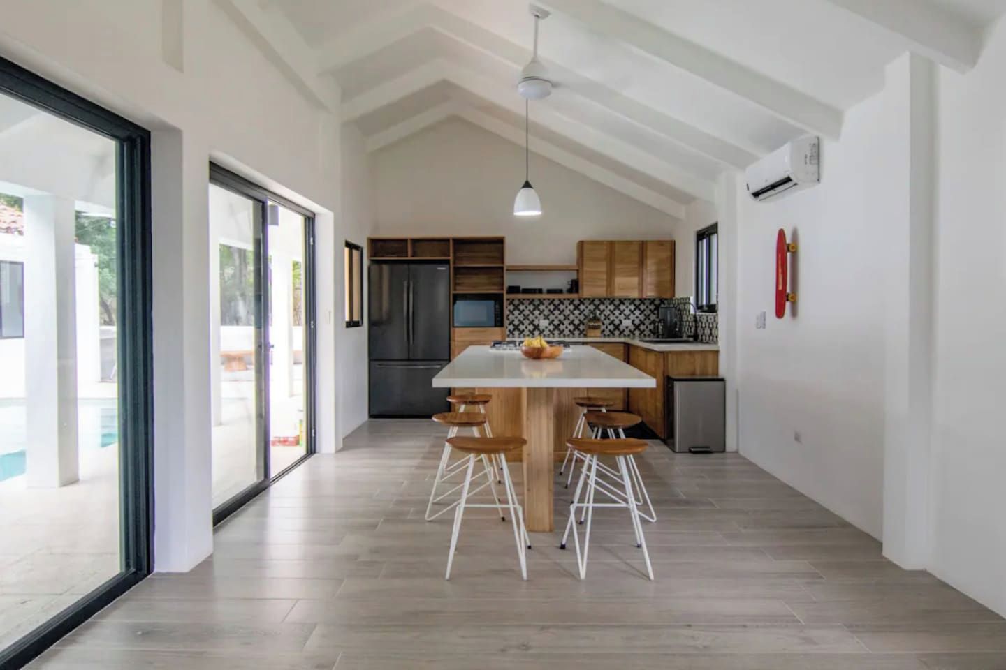 Cozinha moderna com ilha central, banquetas e uma grande janela.