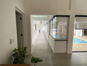 A corridor with a pool visible through a glass door. - Surf Villa in Hacienda Iguana | Pool | Bikes (Rivas)