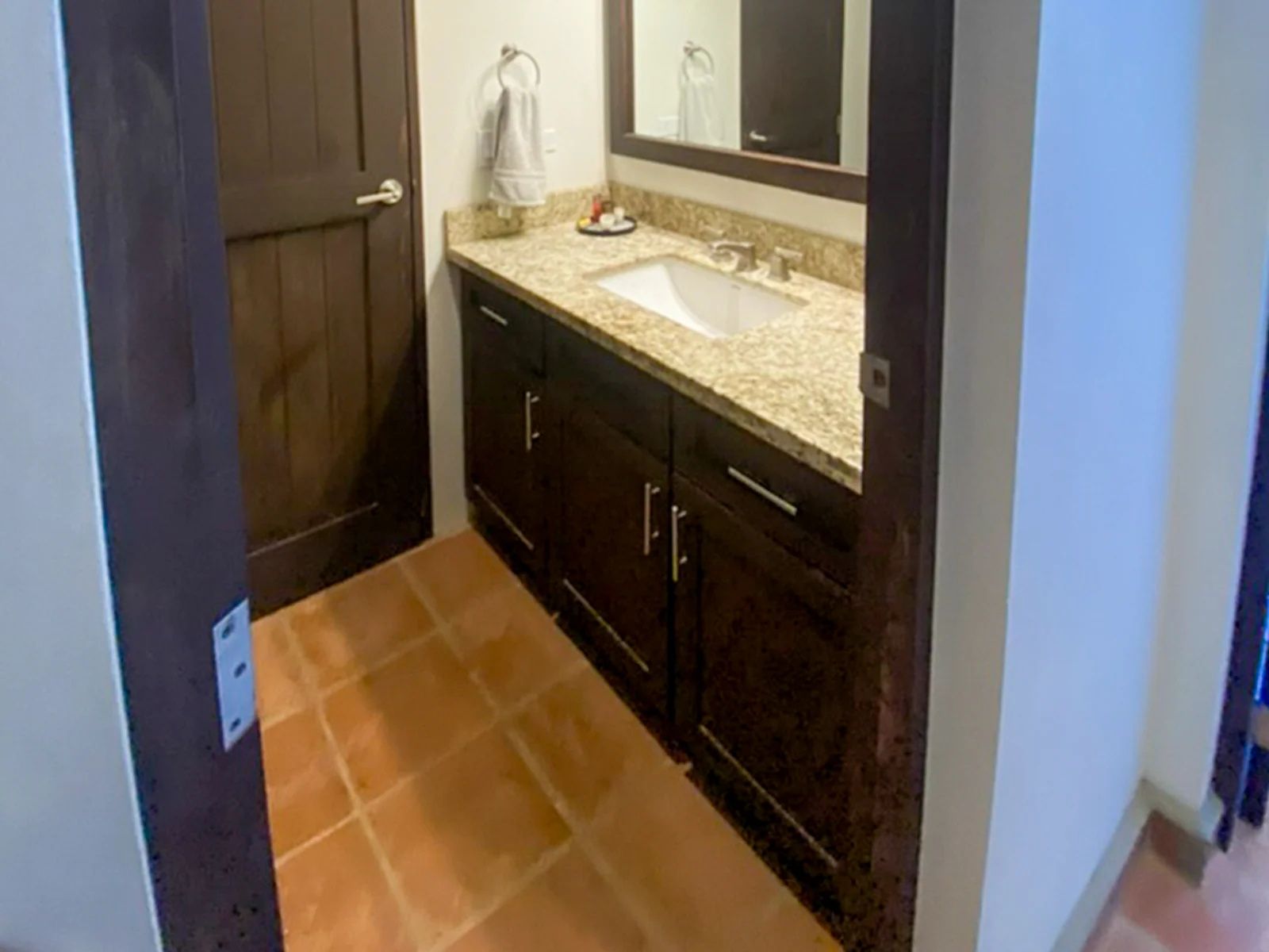 A bathroom with a sink, mirror, and dark wooden cabinets.