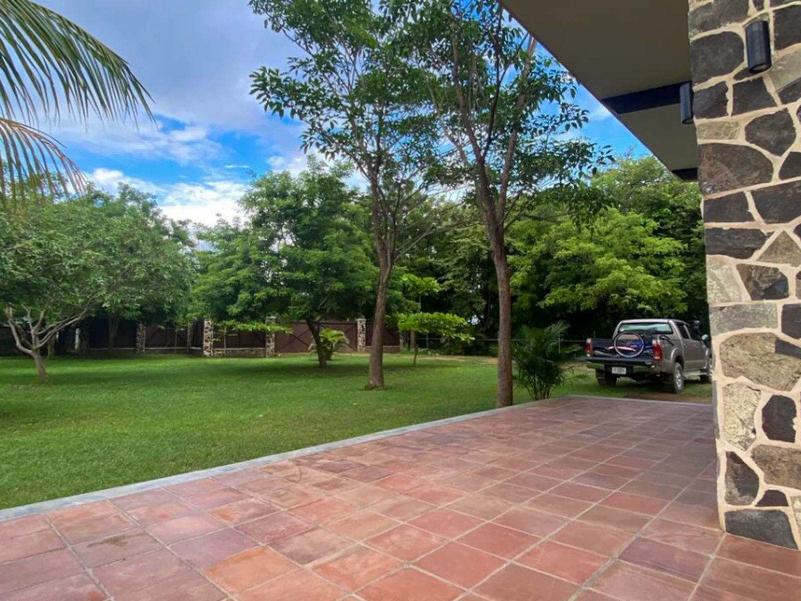 Un patio con muros de piedra y un vehículo estacionado al fondo.