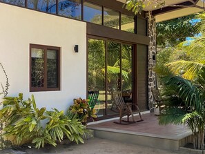 A modern house with a patio, large windows, and tropical plants.