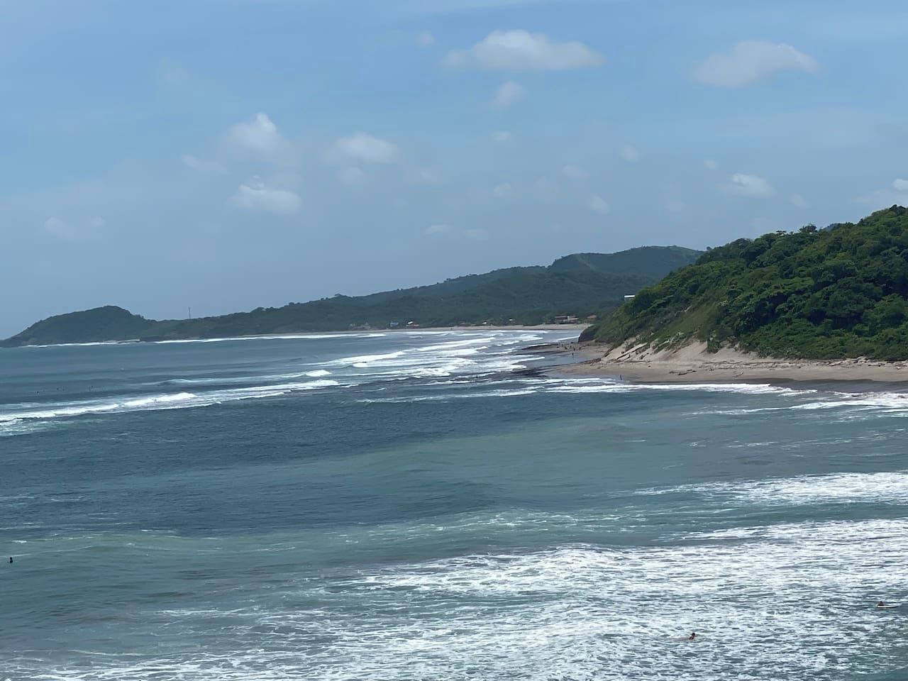 Un paysage côtier avec une plage et des collines en arrière-plan.