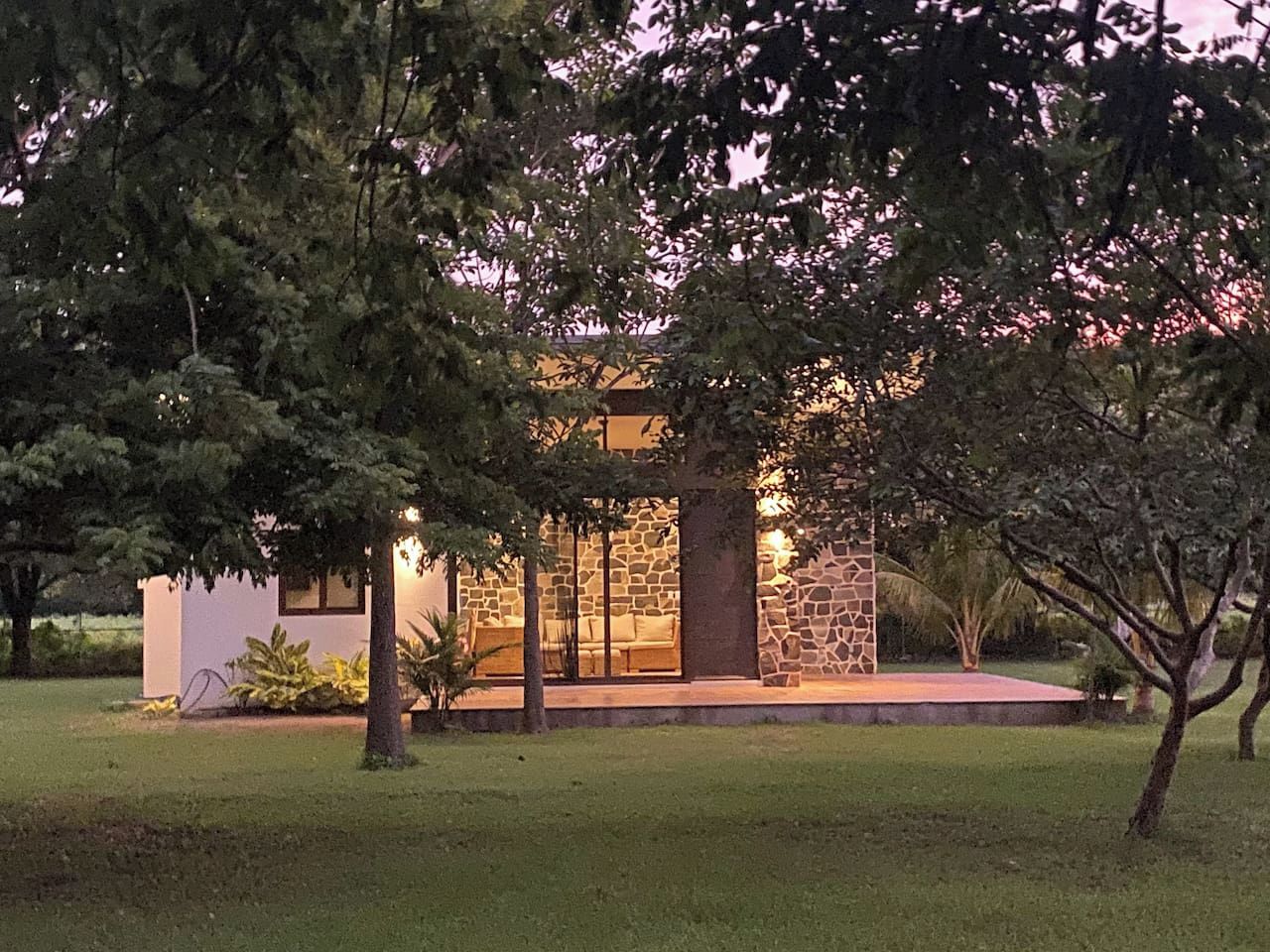 A modern house with a stone facade, a glass door entrance, and a well-maintained lawn.