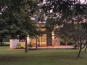 A modern house with a stone facade, a glass door entrance, and a well-maintained lawn.