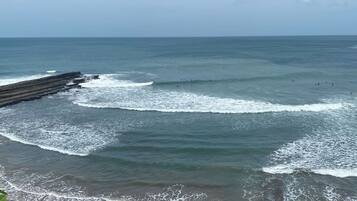 A coastal beach with waves, a wooden jetty, and a clear sky.