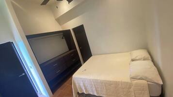 A bedroom with a bed, a wardrobe, a ceiling fan, and a door.