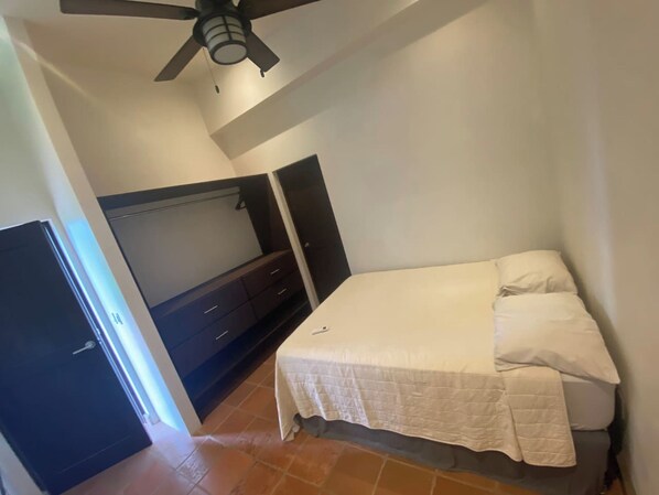 A bedroom with a bed, a wardrobe, a ceiling fan, and a door.