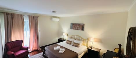 A hotel room with a bed, two bedside tables, a chair, a rug, and a painting on the wall.