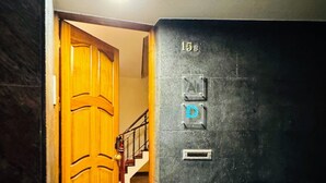 A hallway with a wooden door, a staircase, and a wall with a mail slot and a number '15B'. - DMCharme (Ponta Delgada)