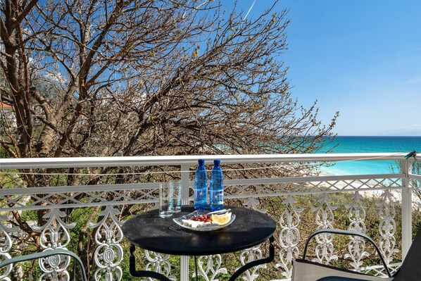 A balcony with a table, two water bottles, a plate with food, and a chair.