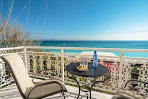 A balcony with a table, chairs, and a view of the sea.