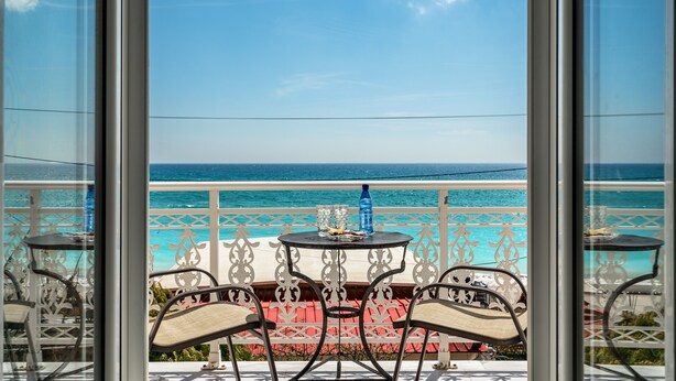 A balcony with a table and chairs, overlooking a beach and the ocean. - Room “Angela sea view 7” with Sea View, Wi-Fi, and Air Conditioning (kefalonia)