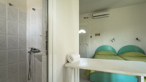 A bathroom with a shower, a white bathtub, and a green bed with a white headboard. - Room “Angela partial sea view 6” with sea view, Wi-Fi, and air conditioning (kefalonia)