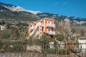 Un immeuble à plusieurs étages doté de balcons, entouré d’arbres et de montagnes.