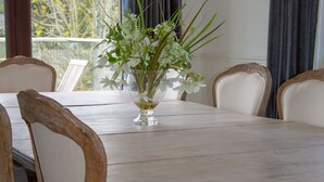 Une table à manger ornée d’un vase de fleurs, entourée de chaises à ossature en bois et dotées d’assises rembourrées.