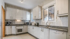 Een moderne keuken met witte kasten, granieten aanrecht, een ingebouwde oven, magnetron en vaatwasser.
