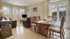 Een ruime woonkamer met een eettafel, stoelen, een bank, een televisie en een open haard.