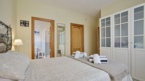 Een hotelkamer met een bed, een spiegel, een kledingkast en een deur naar een badkamer.