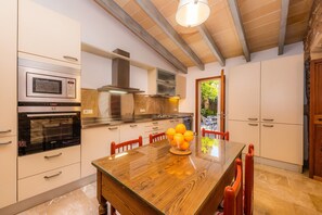 Une cuisine moderne dotée d’appareils électroménagers intégrés, une table à manger en bois et une vue sur l’extérieur.