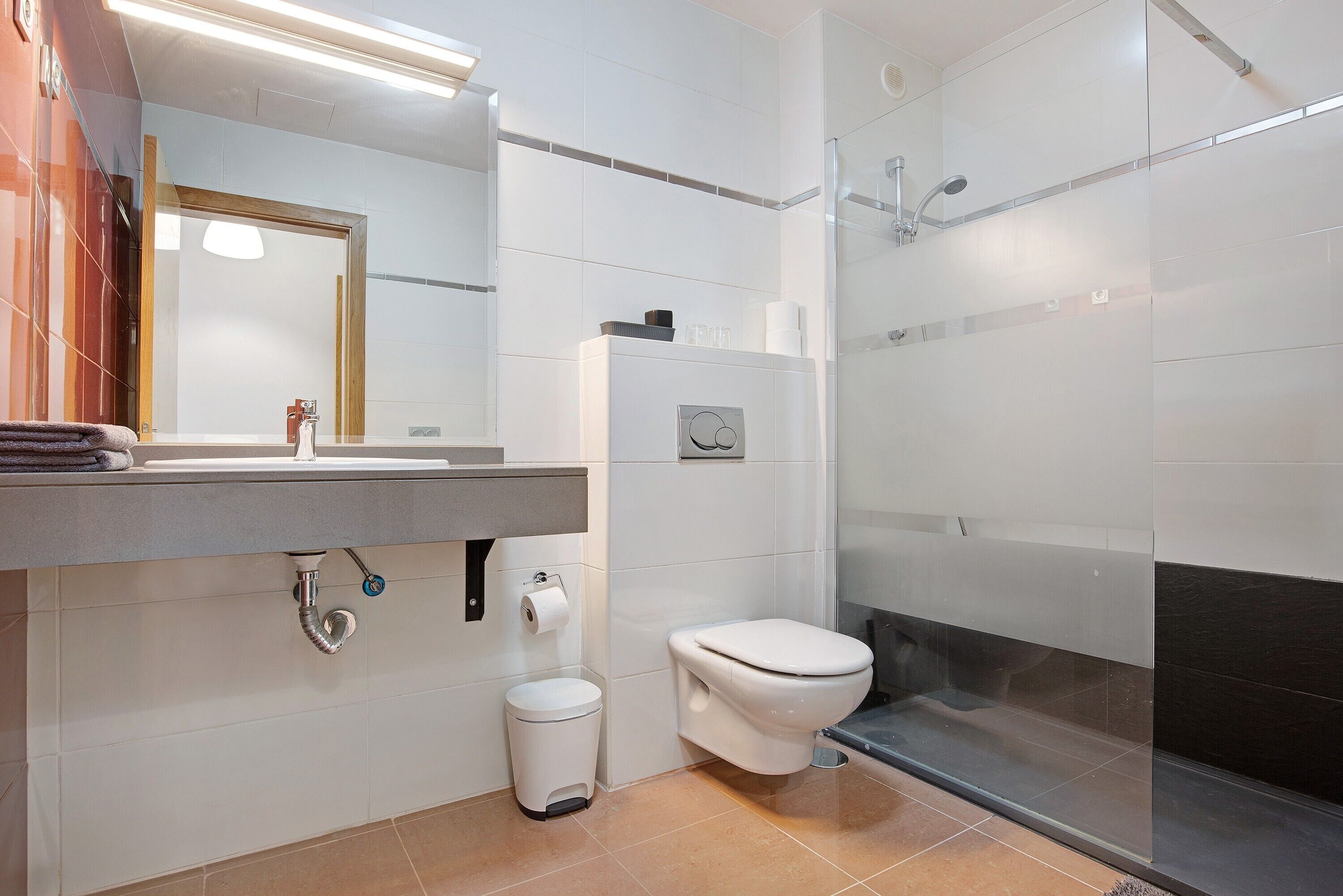 Un baño moderno con inodoro, lavamanos y zona de ducha.