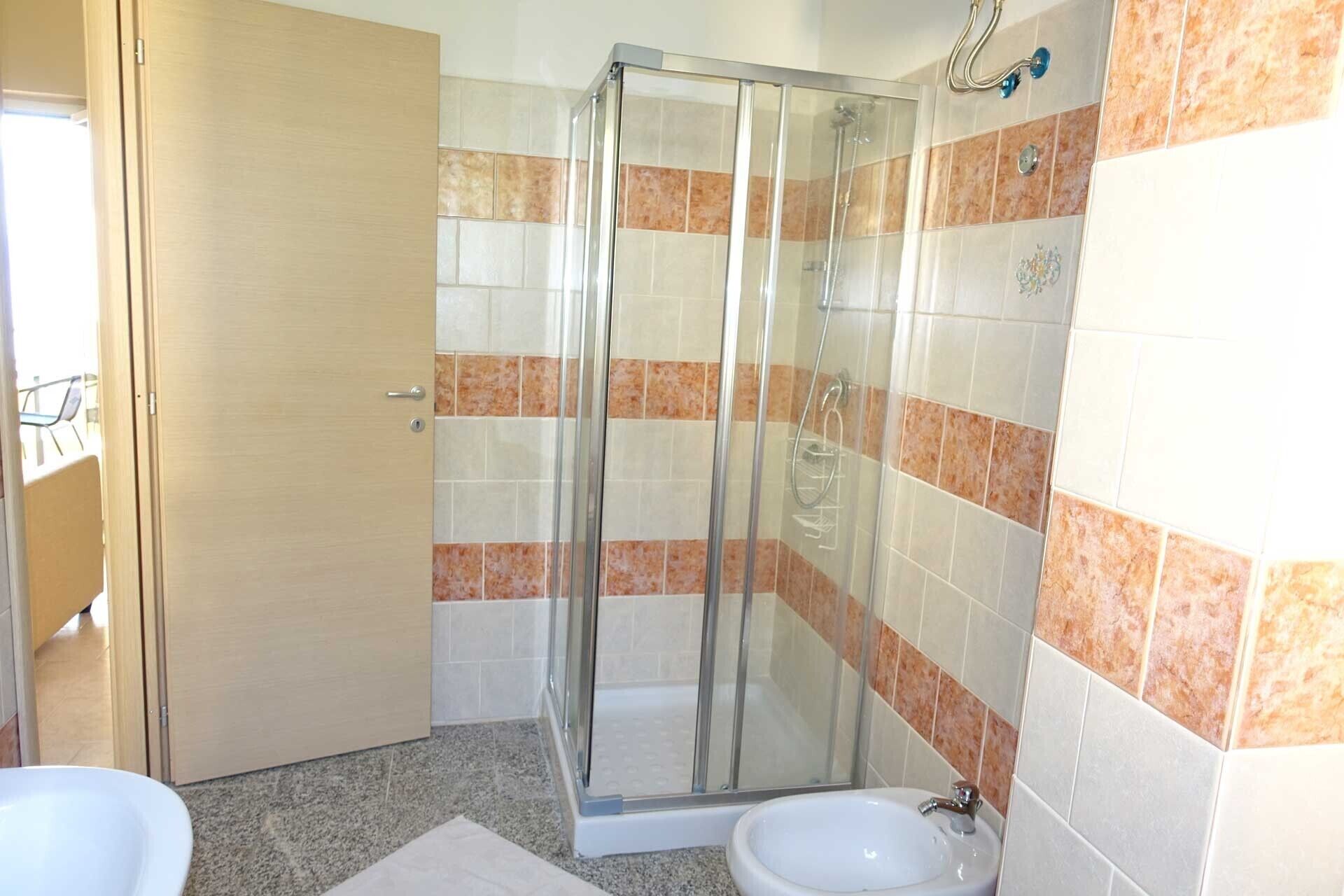 Un baño con cabina de ducha de vidrio, un lavamanos y un inodoro.