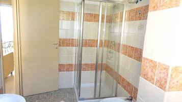Un baño con cabina de ducha de vidrio, un lavamanos y un inodoro.
