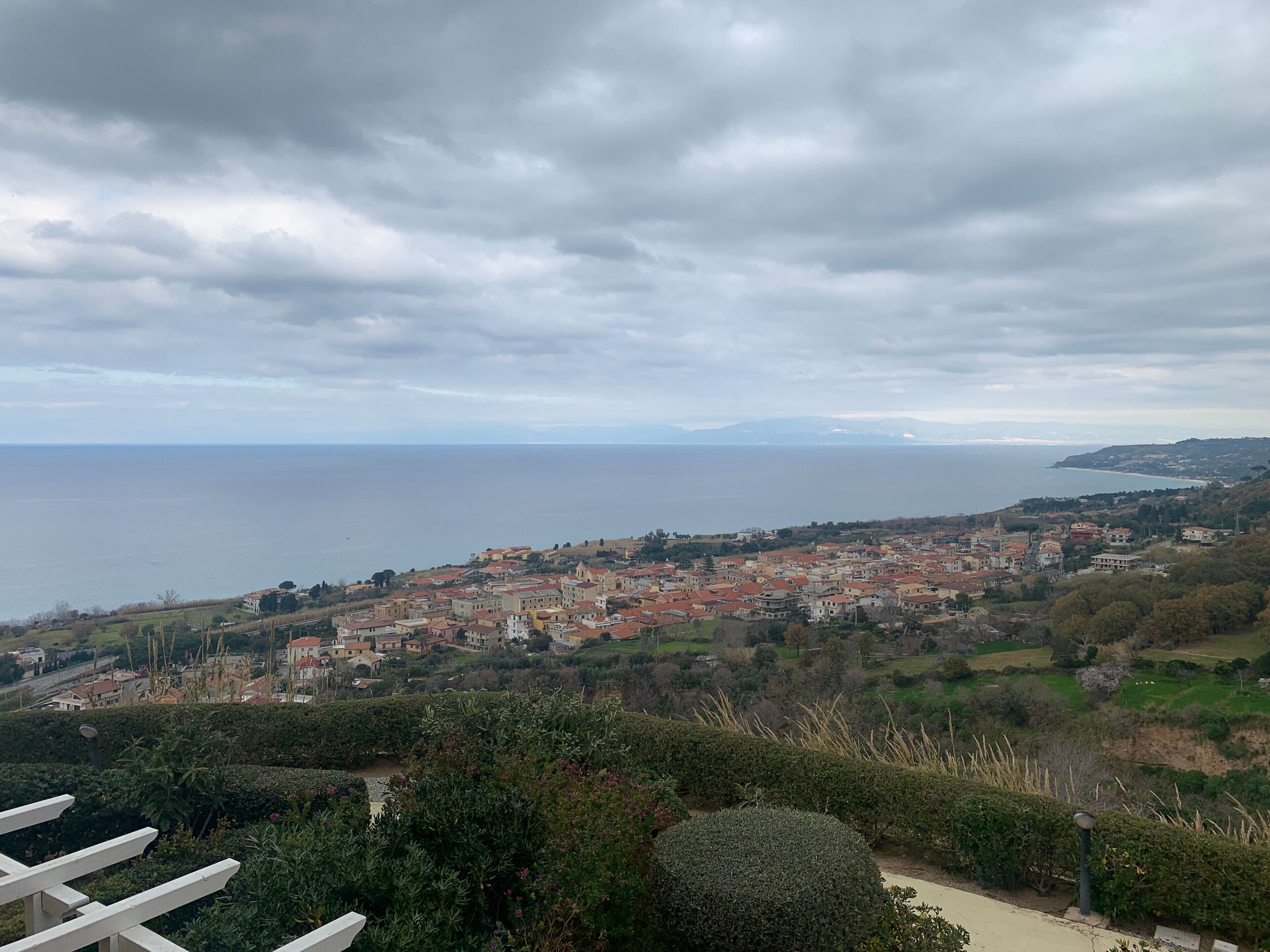 A coastal town with a view of the sea, surrounded by greenery and buildings.