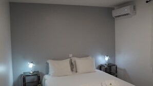 A hotel room with a bed, two bedside tables with lamps, an air conditioning unit, and a wall-mounted light fixture. - Country House 'Tibagota' with Mountain View, Wi-Fi and Air Conditioning (São Brás de Alportel)