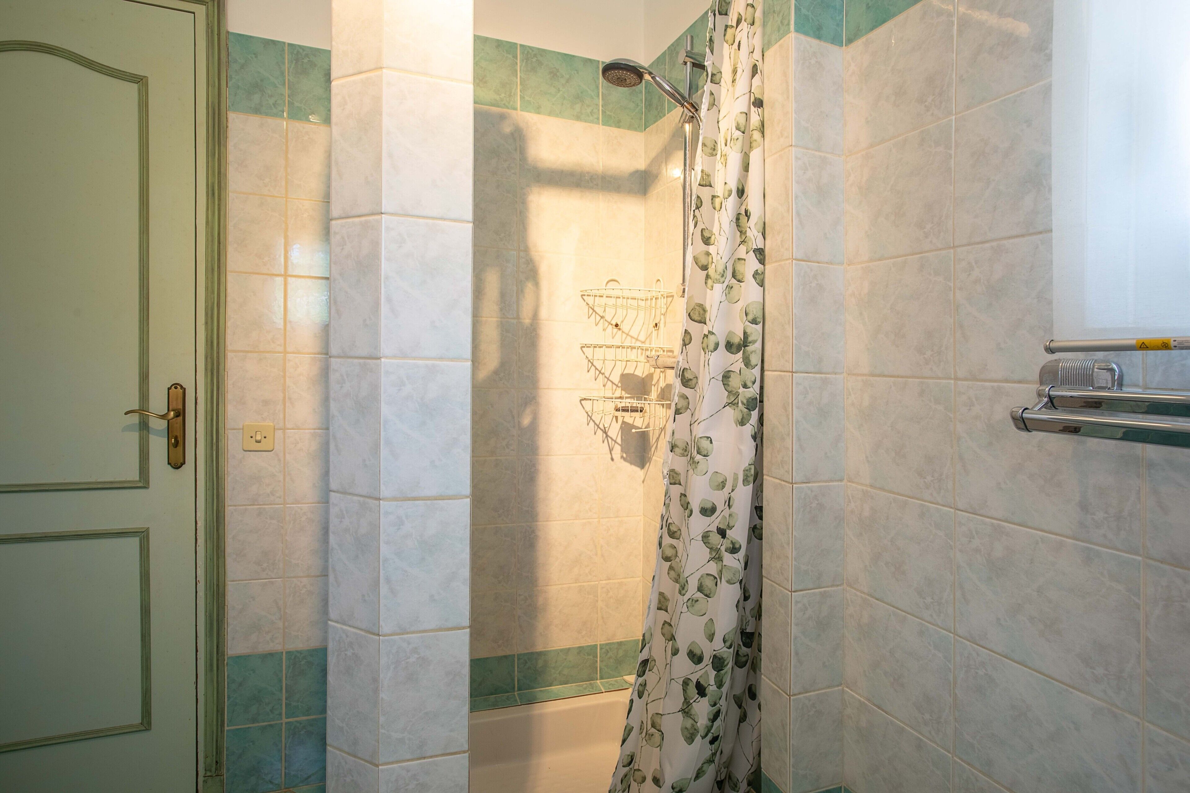 Une salle de bain avec une douche, un porte-serviettes et une porte dotée d’une poignée.