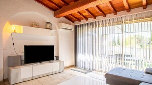 Een woonkamer met een flatscreen televisie, een bank en een bijzettafeltje.