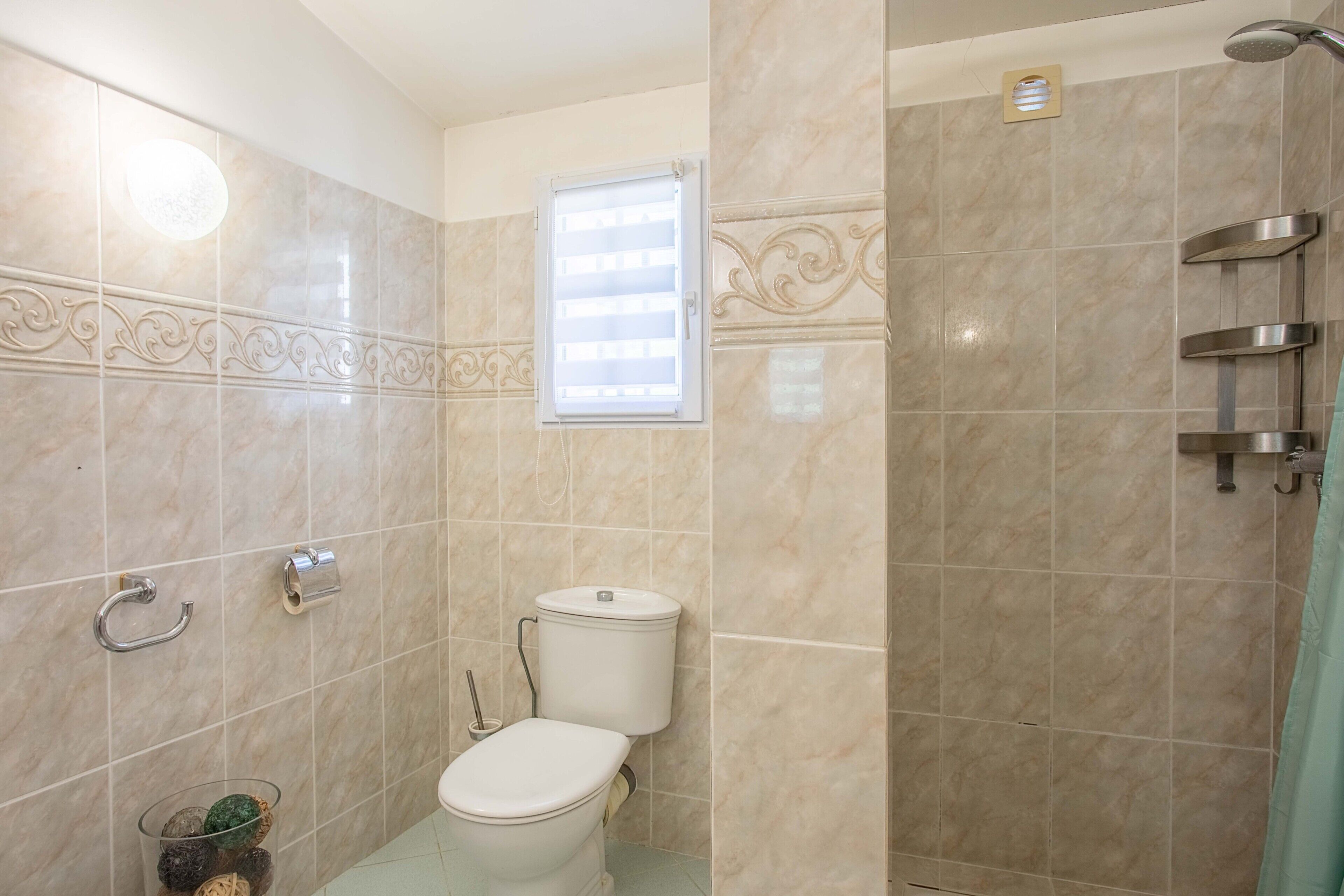 Un baño con inodoro, ducha y ventana.