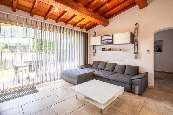 A modern living room with a sectional sofa, a white coffee table, and a large window with blinds.