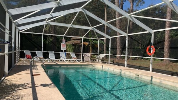 A covered swimming pool with lounge chairs and a lifebuoy. - 08) The Marlin Cottage (Inglis)