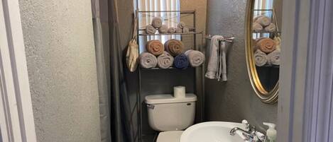 A compact bathroom with a toilet, sink, and towel rack.