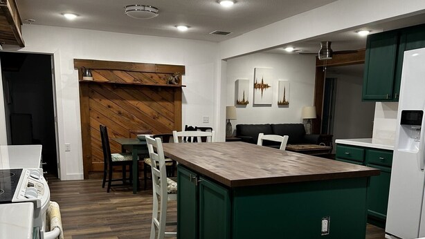 A modern kitchen with a central island, wooden accents, and green cabinetry. - Cookies Cottage , 3 bedroom 2 bath cottage (Inglis)